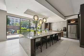 A modern kitchen with a long island and chairs.